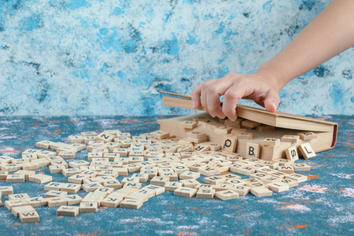 Wooden domino keys with letter printed on them out of a wooden box